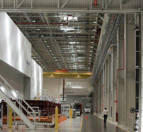 Wide shot of a large industrial facility with freshly repaired concrete floors gleaming under bright lights.